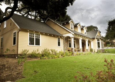 A single-story beige house with white trim and a landscaped lawn.