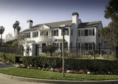 Large two-story white house with black wrought iron fence and landscaping.