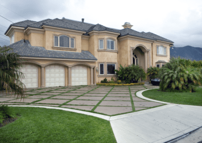 Two-story suburban house with a three-car garage and a landscaped front yard, set against a cloudy sky.