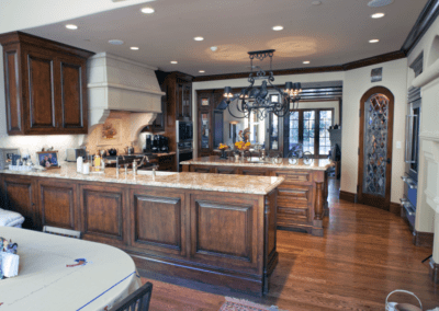 Spacious kitchen featuring wooden cabinets, an island, and a chandelier, with an archway leading to another room.