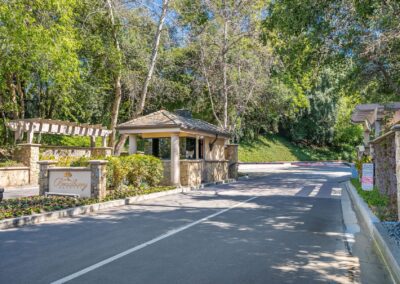 Entrance gate with a small covered structure, a sign reading "Crossbow," surrounded by trees and landscaped areas.