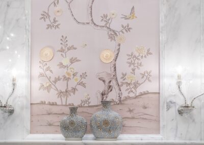 Elegant wallpaper with floral and bird design, two ornate vases in the foreground, marble accents, and two glass sconces on either side.