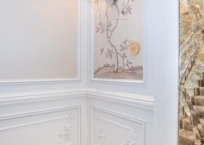 Elegant corner with ornate paneling, floral wallpaper, and a decorative wall sconce.